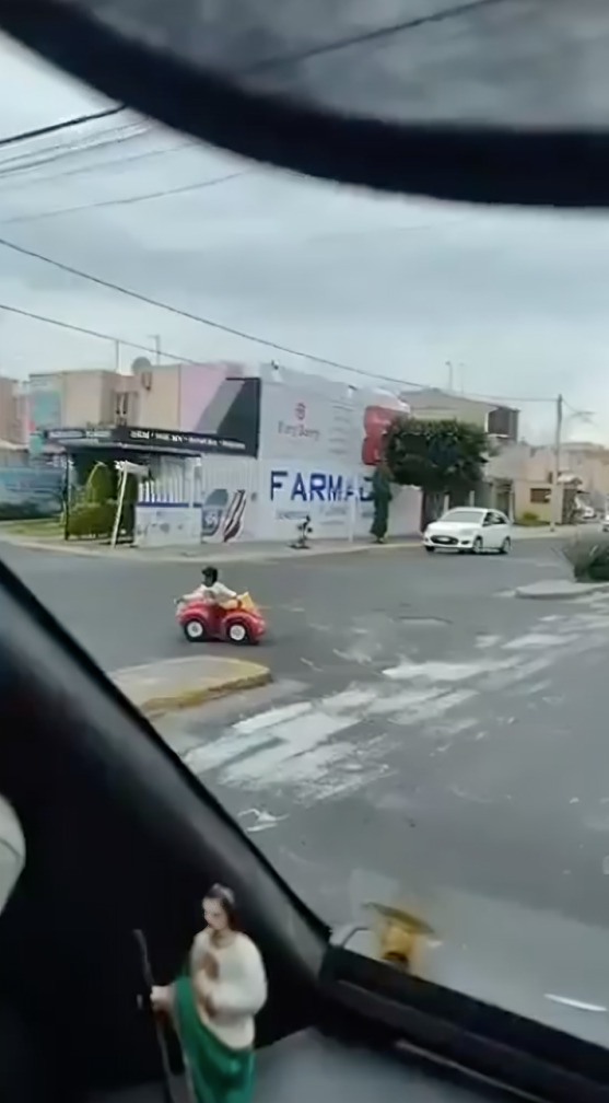 Niño cruza peligrosa avenida en carro de juguete